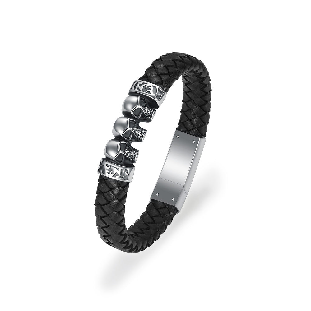 Black Skull Bracelet Urn for men with three silver skulls on braided leather. Features secure magnetic clasp for storing keepsakes discreetly.