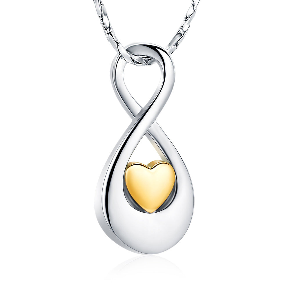 Infinity Gold Tone Heart Pendant in stainless steel featuring a gold-tone heart centerpiece. Includes ashes compartment, polishing cloth, and velvet bag.