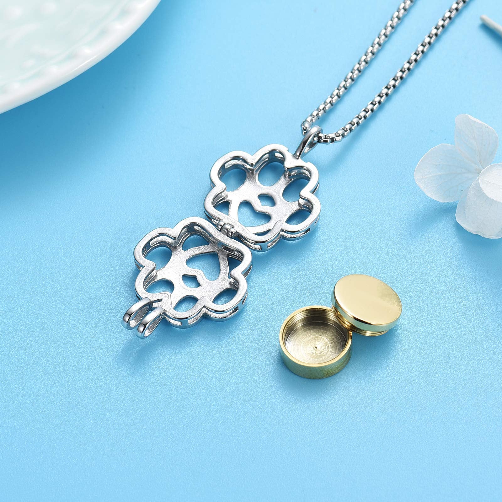 Open Paw Print Urn Pendant showing internal gold ash container. Stainless steel pet memorial necklace with discreet ash storage compartment.