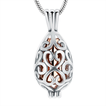 Rose gold urn pendant in teardrop shape with intricate stainless steel filigree design. Keepsake necklace for ashes with elegant finish.