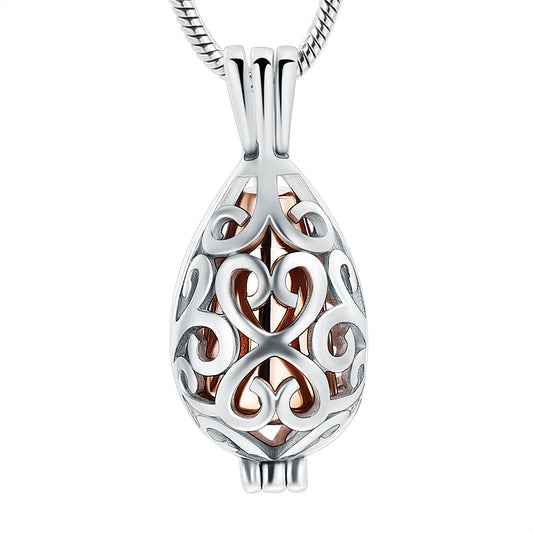 Rose gold urn pendant in teardrop shape with intricate stainless steel filigree design. Keepsake necklace for ashes with elegant finish.