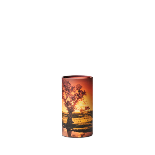 Sunset Scattering Urn - Small features a compact cylindrical design with a serene sunset and tree landscape, ideal for memorial ceremonies. Elegant and portable for scattering ashes.